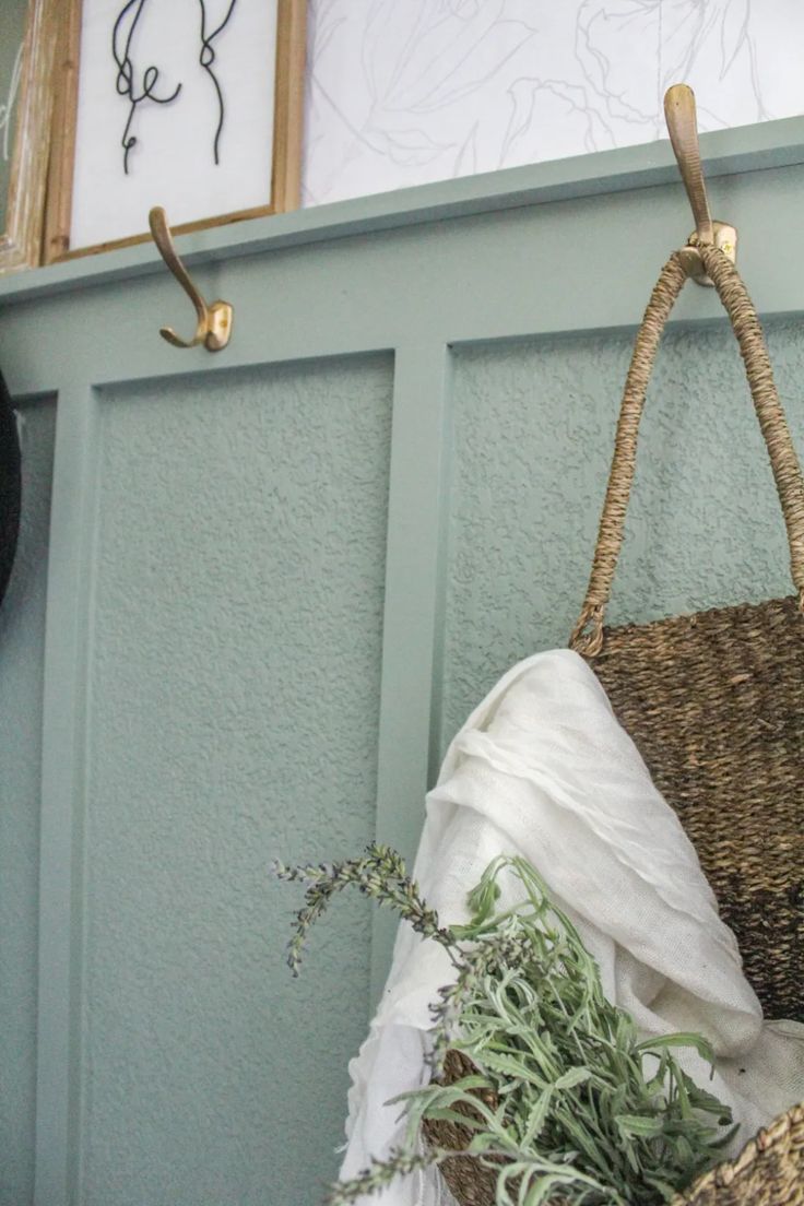 a wicker basket hanging from a hook on a wall next to a potted plant