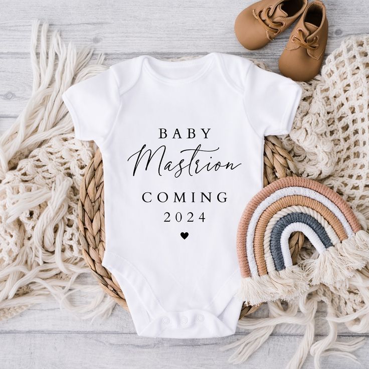 a white baby bodysuit with the words baby mission coming next to it and some shoes