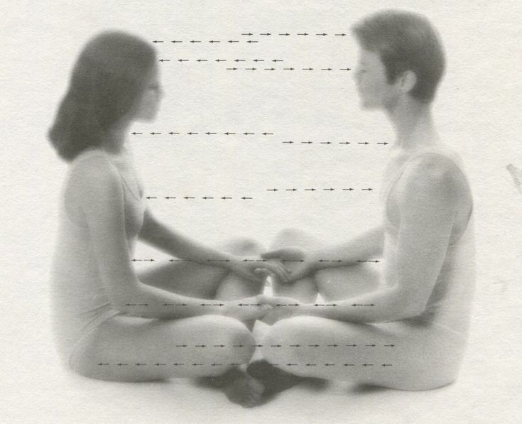 a man and woman sitting on the ground with their hands together