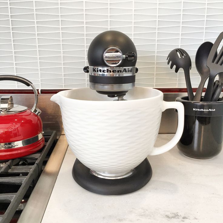 a kitchen aid mixer sitting on top of a counter next to utensils and spoons