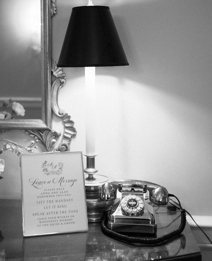 an old fashioned telephone sitting on top of a table next to a framed sign and lamp