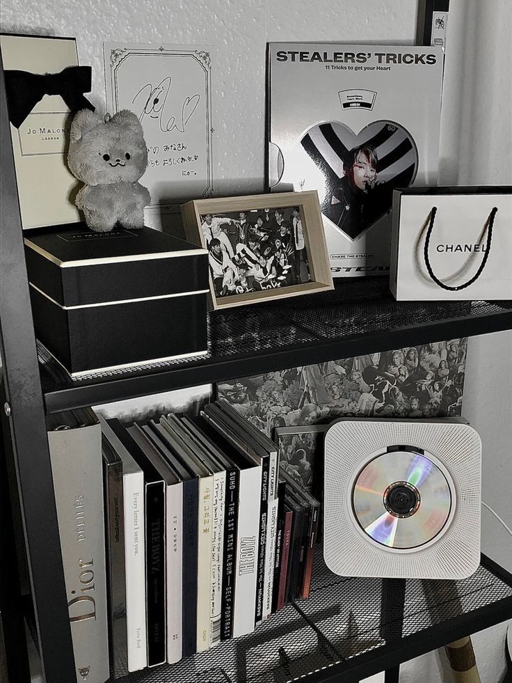 a shelf filled with books and cds next to a stuffed animal on top of it