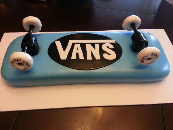 a cake shaped like a skateboard with the word vans on it and two white knobs