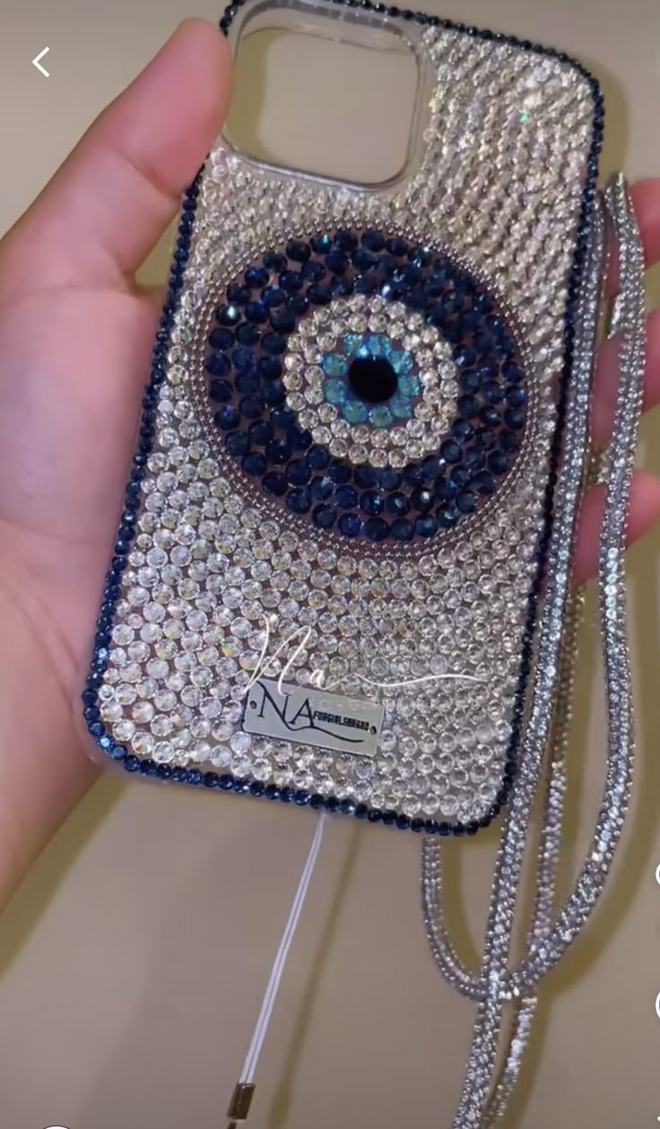 a hand holding a cell phone case with an evil eye on the front and side