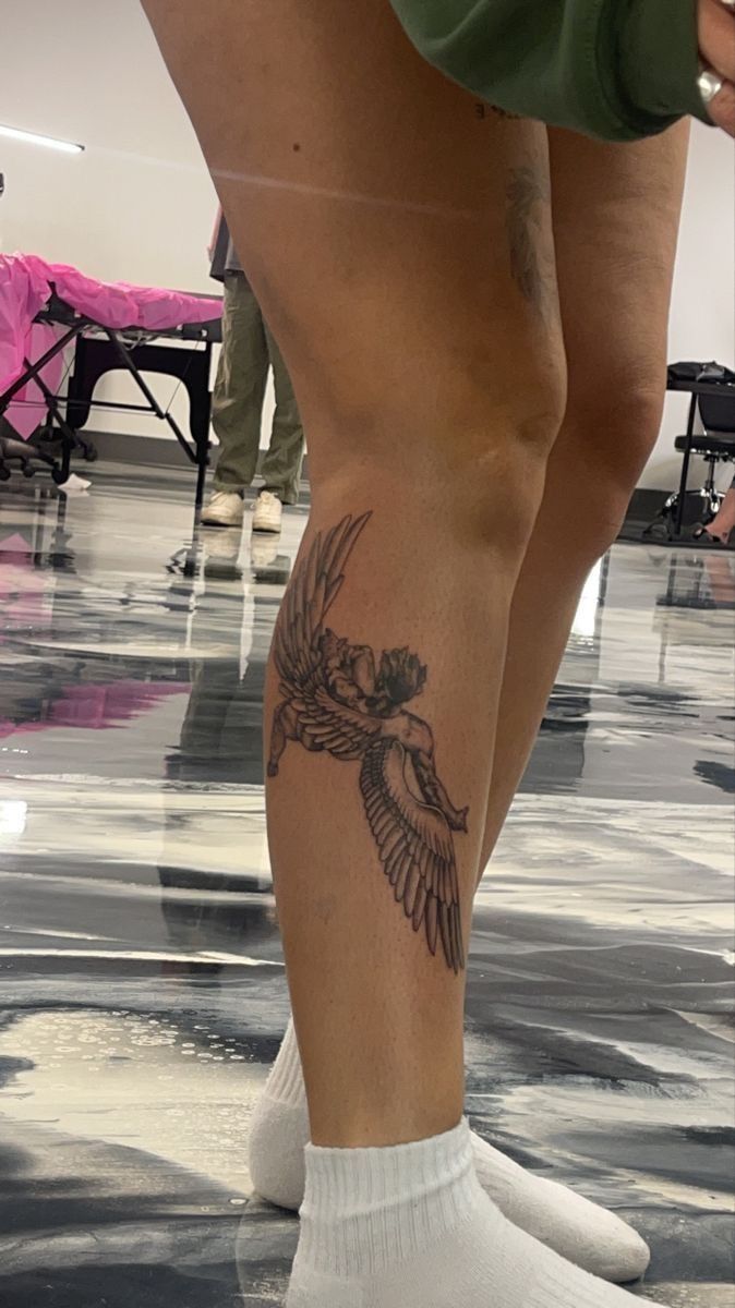 a person with a bird tattoo on their leg and legs, standing in the middle of a room