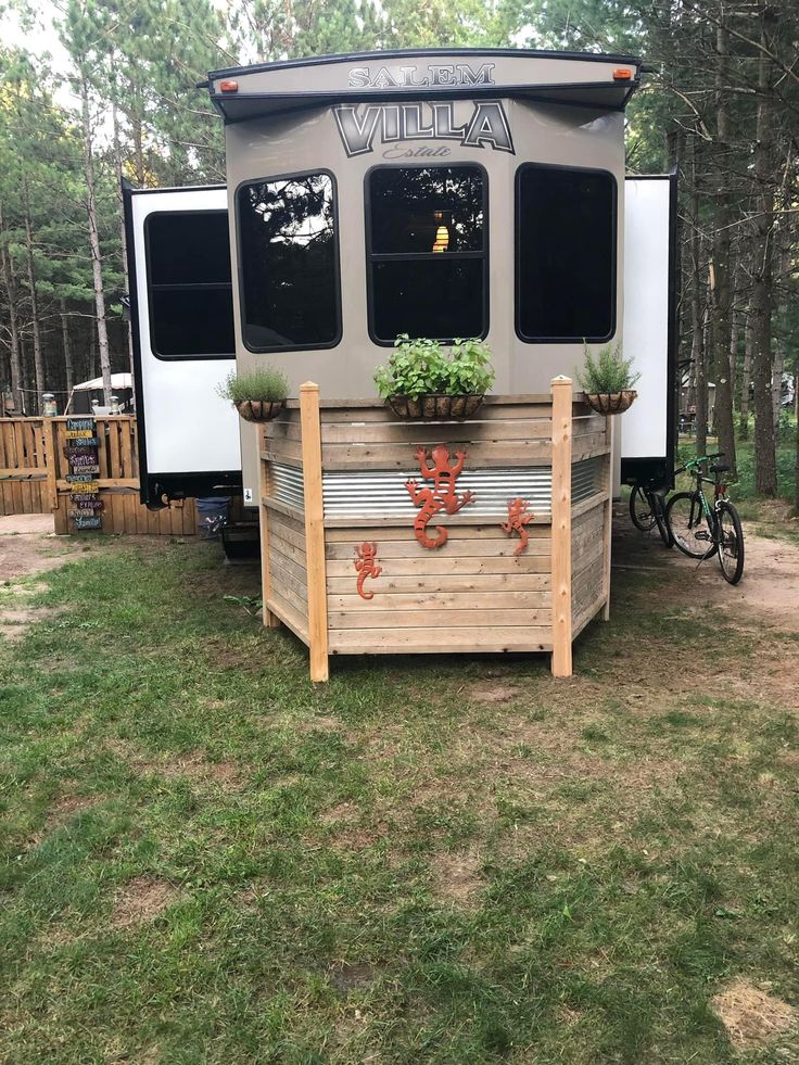 an rv is parked in the grass with potted plants