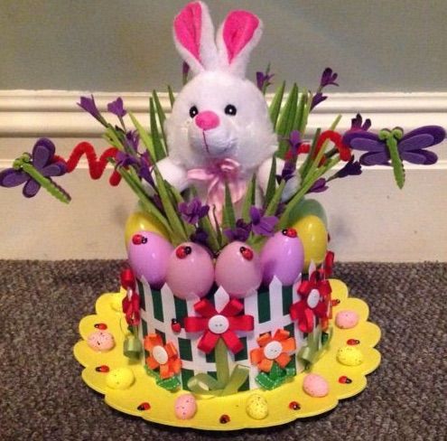 a white bunny sitting on top of a cake with flowers and eggs in the middle