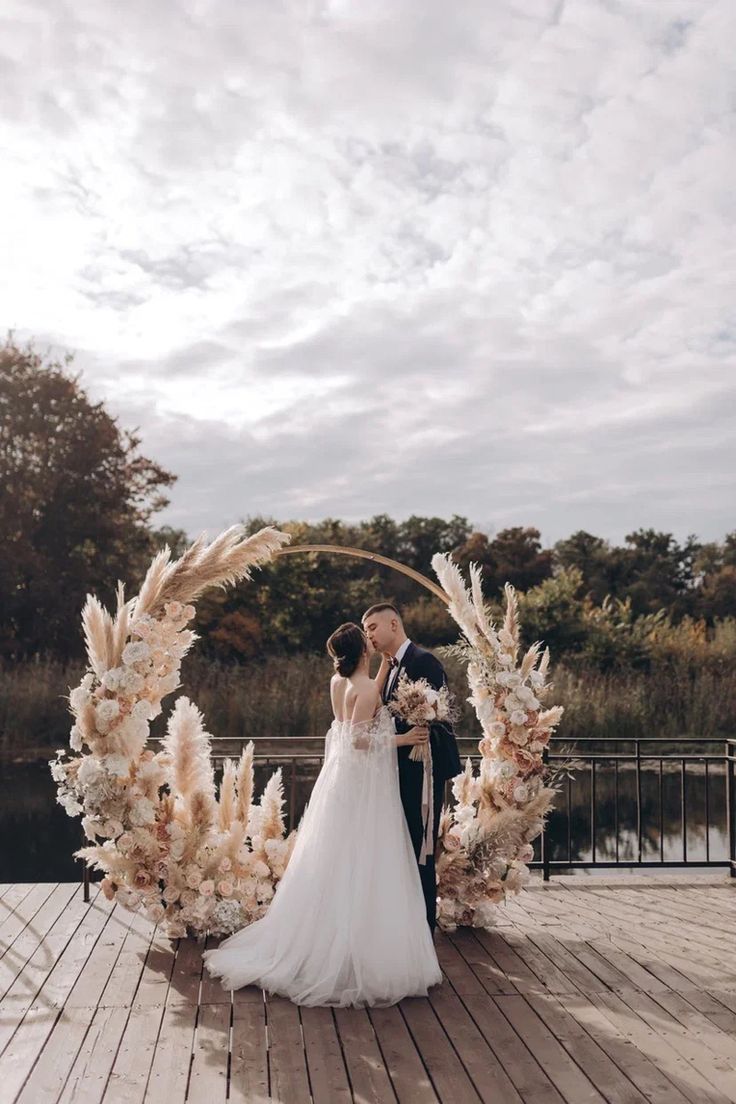 a bride and groom standing in front of an arch made out of pamodia