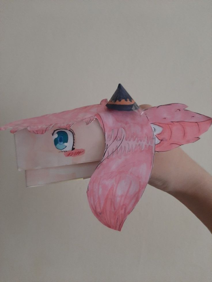 a pink bird with a hat on it's head is being held by someone