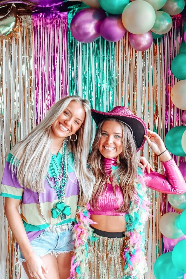 two beautiful young women standing next to each other in front of balloons and streamers