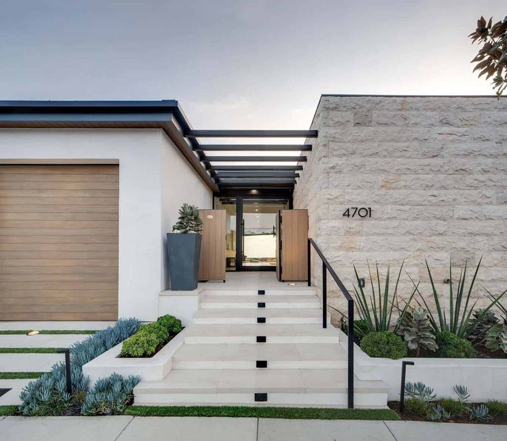 a modern house with stairs leading up to the front door