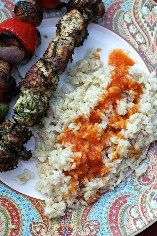 a plate with rice, meat and vegetables on it next to a side of sauce