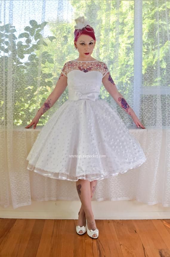 a woman in a white dress standing on a wooden floor with her hands out to the side