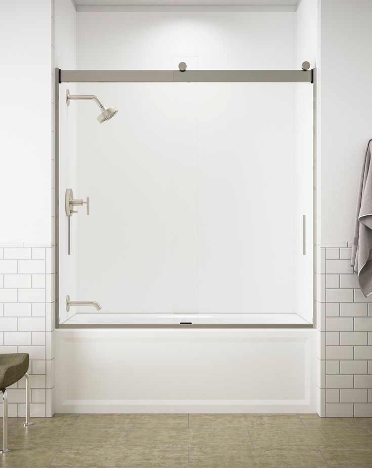 a white bathroom with a glass shower door and towel rack on the wall next to it