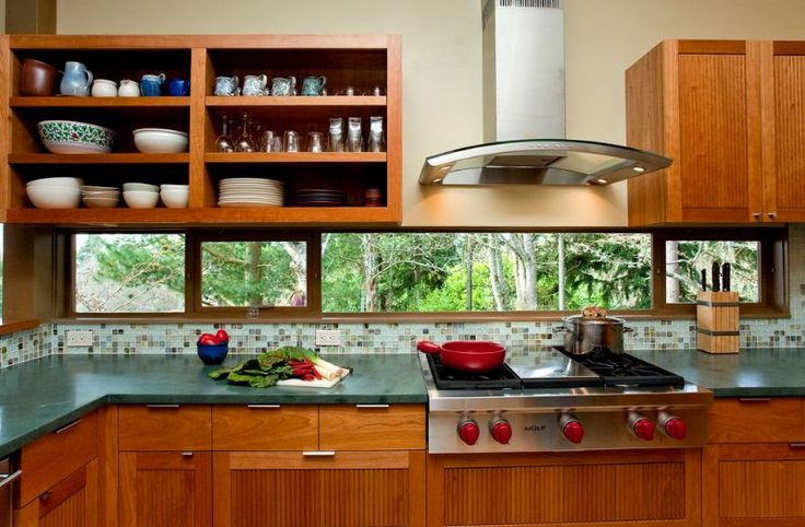 a kitchen with wooden cabinets and stainless steel appliances, including an oven hood over the range