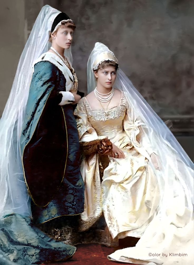 an old photo of two women dressed in wedding attire, one wearing a veil and the other with a tiara