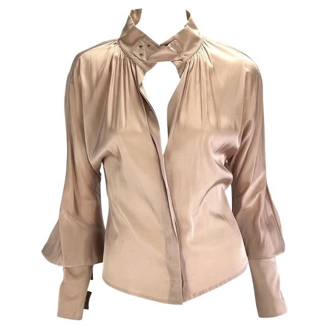 This beige silk long-sleeve Gucci top, designed by Tom Ford for the Fall/Winter 2003 collection, features luxurious silk with grommet and strap accents. The top has long cuffs with strap closures leading to voluminous sleeves. A matching strap is present at the neck, which can be worn open or closed. The blouse is finished with a stand-up collar and a deep neckline. Approximate measurements: Size - 40IT Shoulder to hem: 20" Bust: 30 - 36" Waist: 28" Shoulder to cuff: 30" Underarm to cuff: 21" 87% silk, 13% spandex Tom Ford Top, Gucci By Tom Ford, Gucci Top, Kimono Shirt, Gucci Brand, Beige Silk, Gucci Outfits, Printed Tunic Tops, Chic Blouses