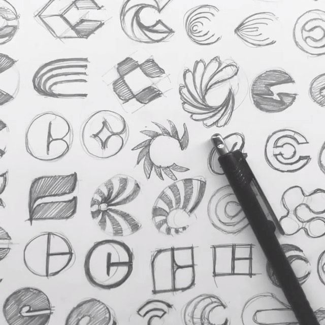 a pen is sitting on top of a drawing paper with various symbols and letters drawn in it