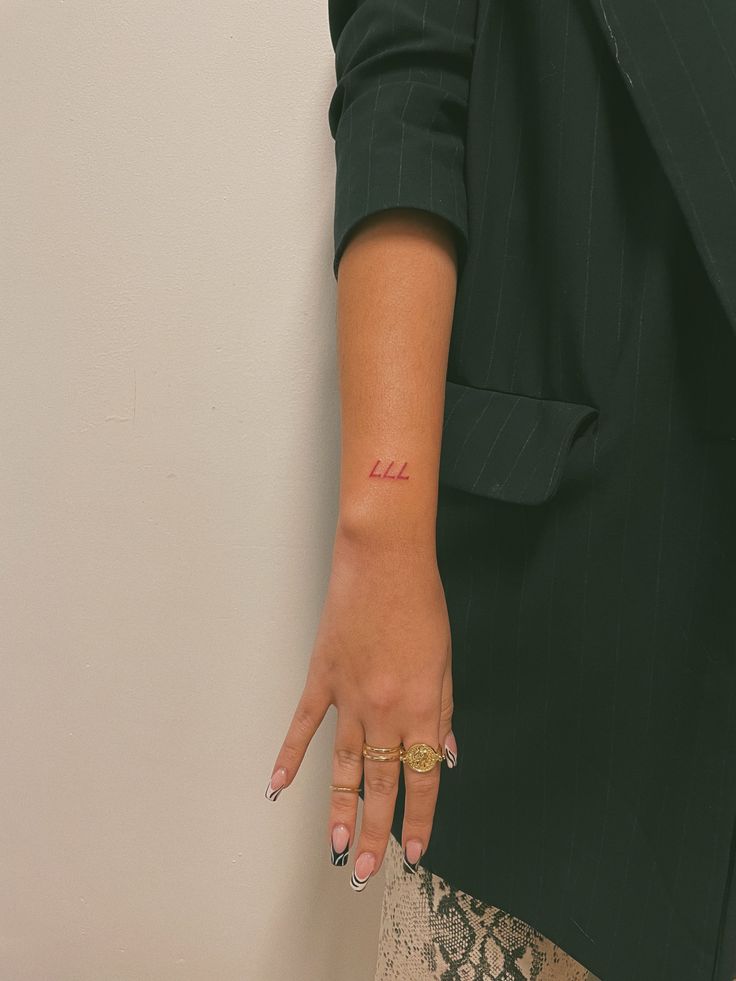 a woman's hand with a small tattoo on her left wrist and the word love written in red ink