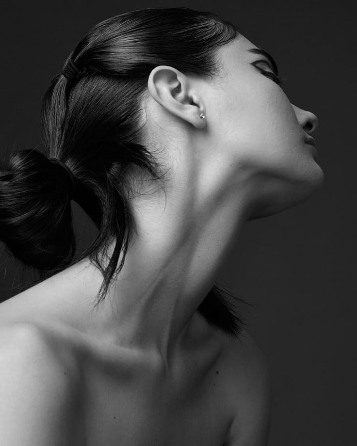 a black and white photo of a woman's face with her hair in a bun