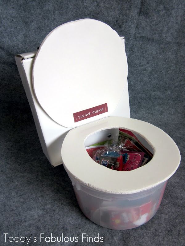 a white toilet with its lid open and some items in the container inside that is empty