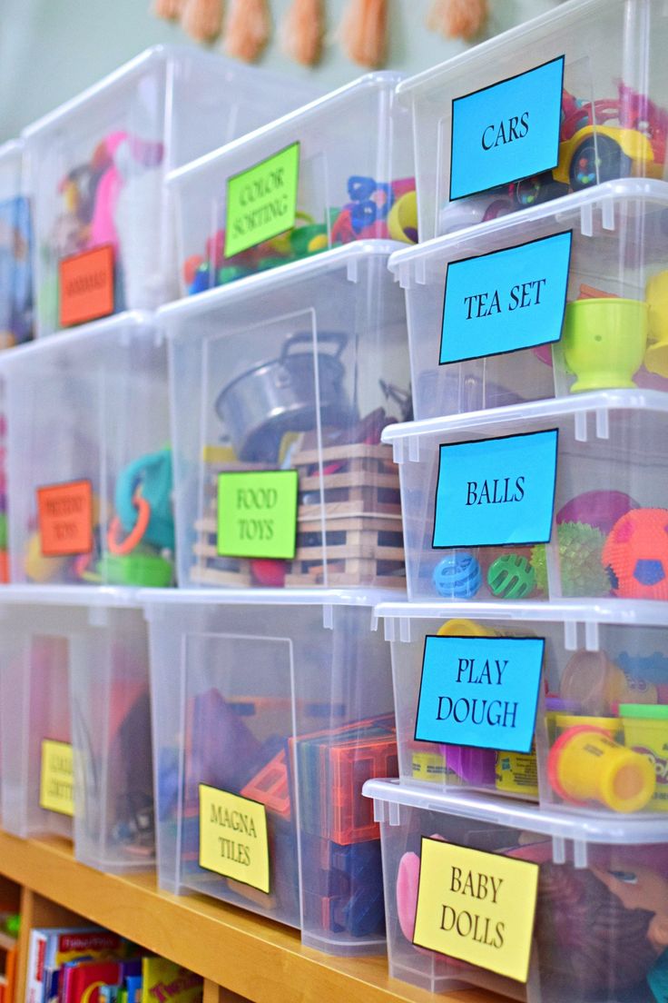 plastic bins filled with lots of toys on top of a wooden shelf