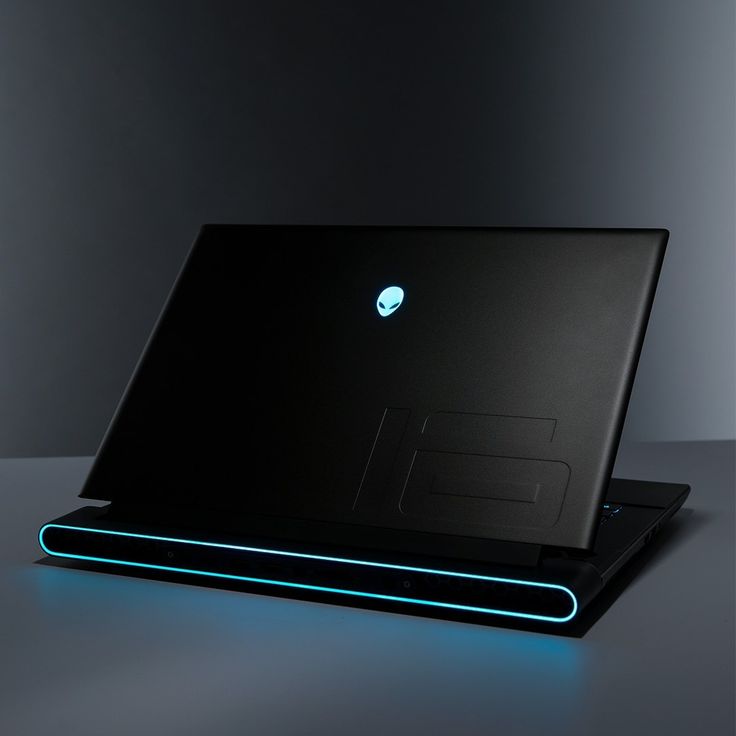 an alien laptop is lit up with blue light on the keyboard and back cover,