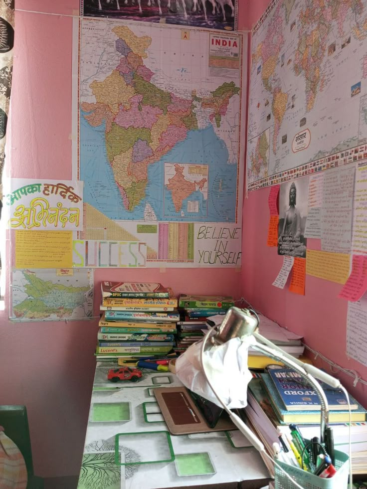 a desk with many books on it and a map hanging from the wall behind it