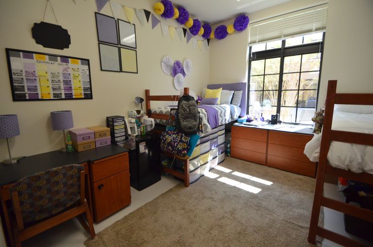 a dorm room with bunk beds, desks and pictures on the wall above them