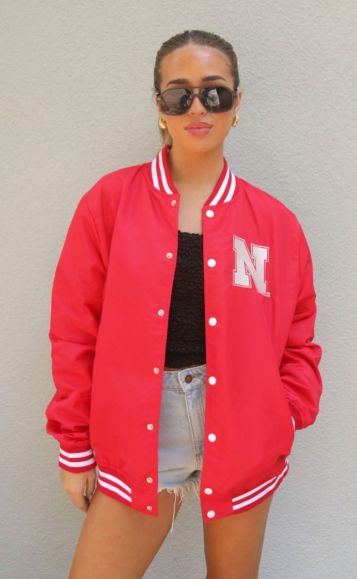 Looking for the ultaimte gameday outfit? Look no further than this vintage inspired varisty jacket. This Nebraska red snap front jacket has the "N" logo on the front and "Huskers" on the back. 


Mary Claire is 5’9” and is wearing size medium

medium measurements: 47” bust | 29” length

100% polyester


WE ONLY OFFER STORE CREDIT FOR RETURNS! Feel free to email us at orders@shopriffraff.com or DM us with any questions regarding fit, styling, or our return policy in general. Varsity Long Sleeve Outerwear For Game Day, Sporty Outerwear For Game Day In Fall, Sporty Fall Outerwear For Game Day, Collegiate Varsity Jacket With Baseball Collar For Spring, Collegiate Track Jacket For Game Day In Fall, Team-colored Outerwear For Game Day In Fall, Game Day Outerwear With Ribbed Cuffs For Sports Season, Collegiate Track Jacket For Game Day, Collegiate Style Track Jacket For Game Day In Fall