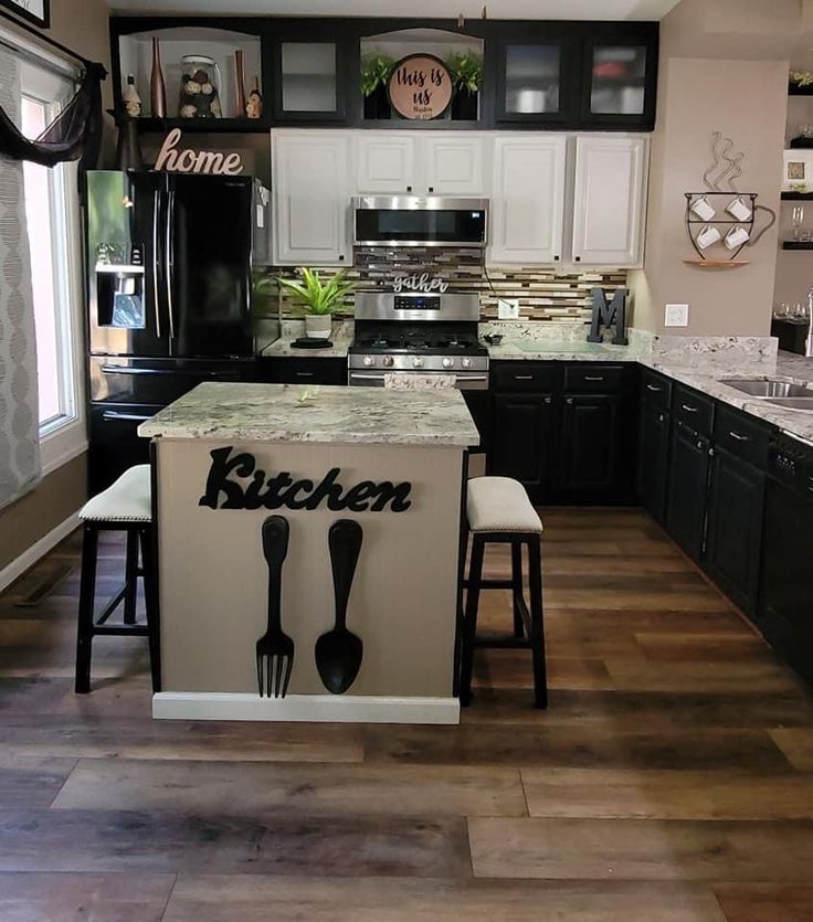 a kitchen with black cabinets and white countertops has an island with utensils on it