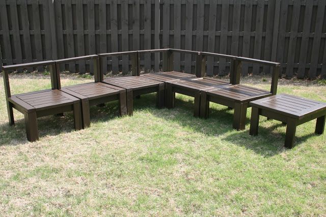 a wooden bench sitting on top of a grass covered field next to a black fence