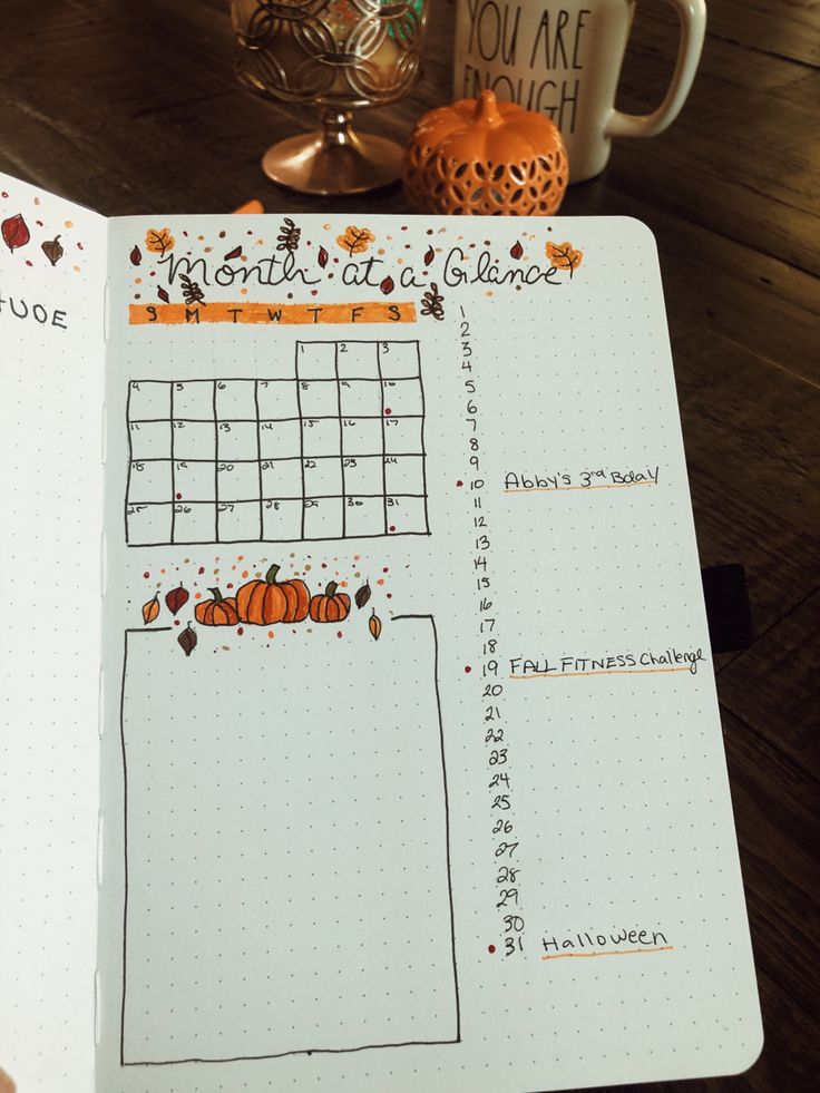 an open planner with pumpkins and leaves on it, next to a cup of coffee