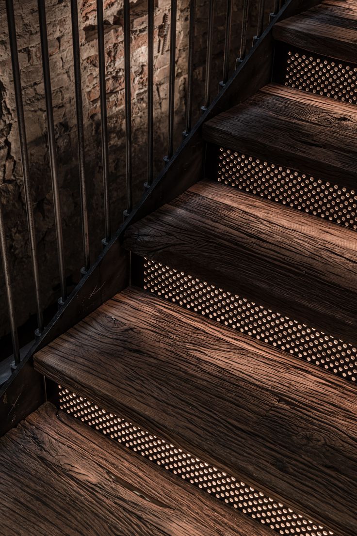 the stairs are made of wood and have metal handrails on each side, along with perforated treading