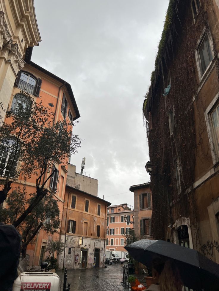 people are walking down an alleyway with umbrellas on a rainy day in the city