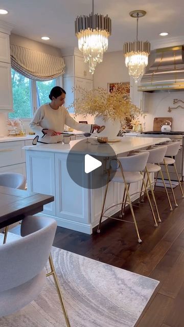 a woman standing in a kitchen preparing food on top of a counter next to chairs