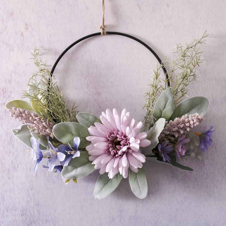 a wreath with flowers and greenery hanging on the wall