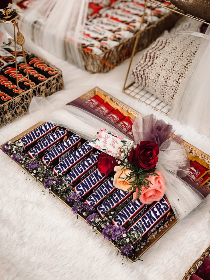 there are many candy bars laid out on the table with flowers and ribbons around them