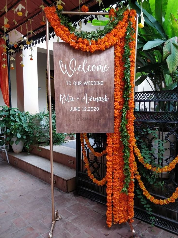 a welcome sign is decorated with orange flowers and greenery in front of a building