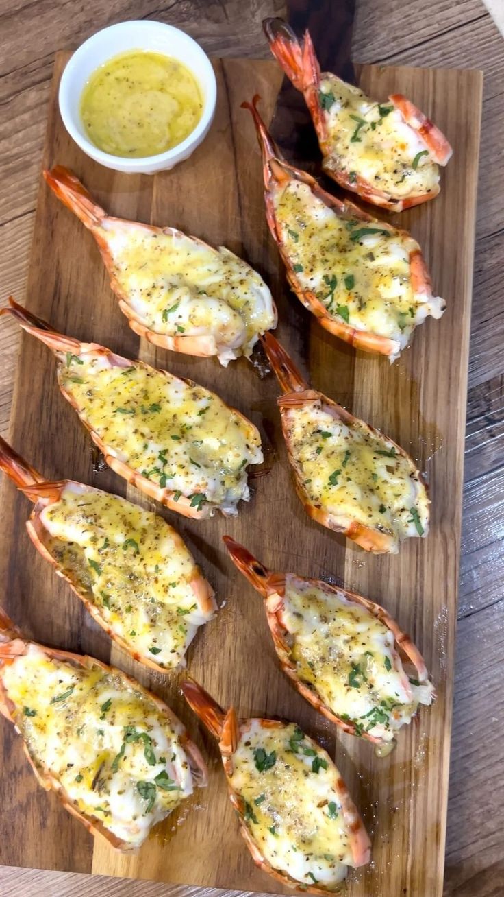 several cooked lobsters on a cutting board with dipping sauce