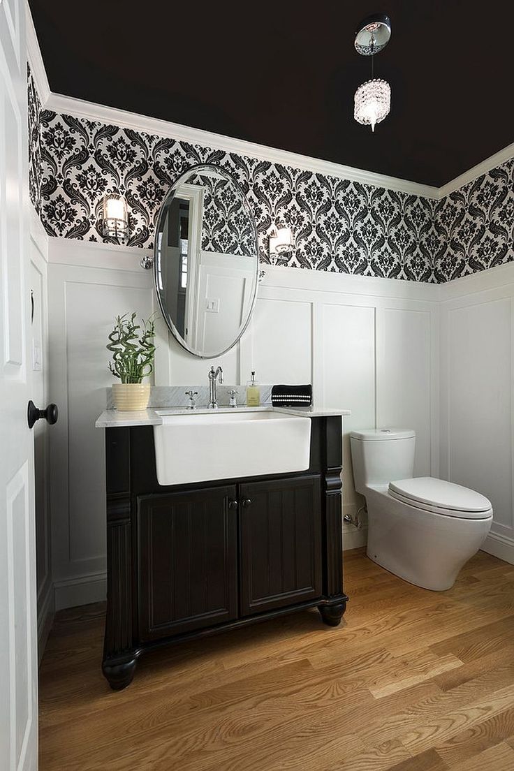 a bathroom with black and white wallpaper, wood flooring and a large mirror above the sink