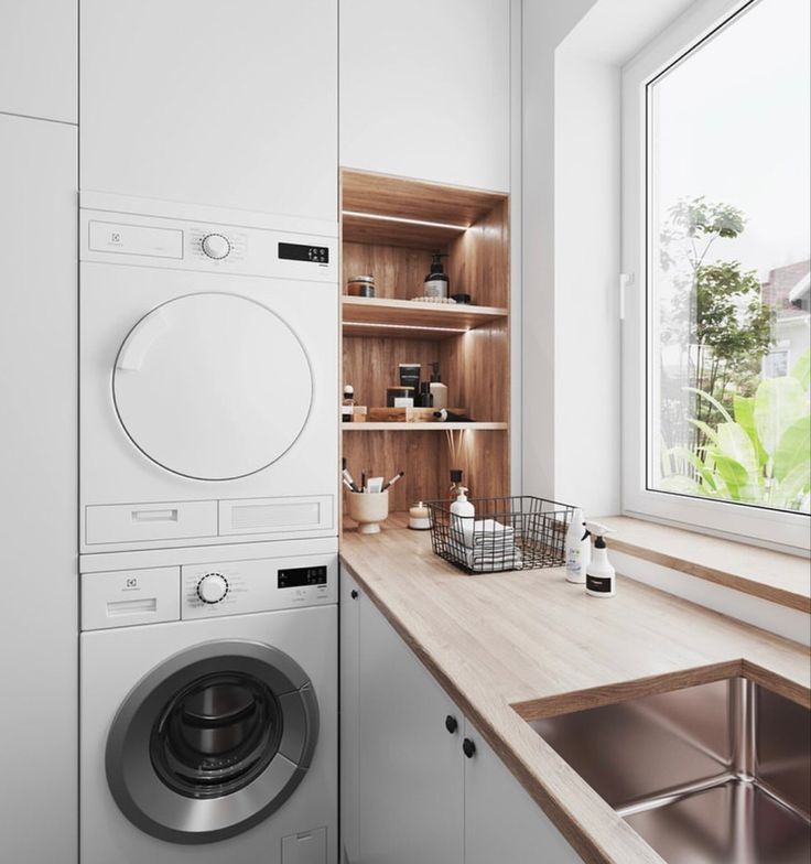 a washer sitting next to a window in a room with wooden counter tops and cabinets