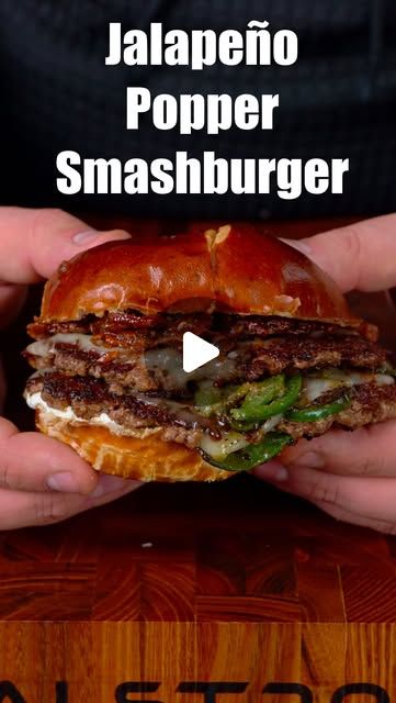 a person holding a sandwich in their hands with the caption jalapeno popper smashburger