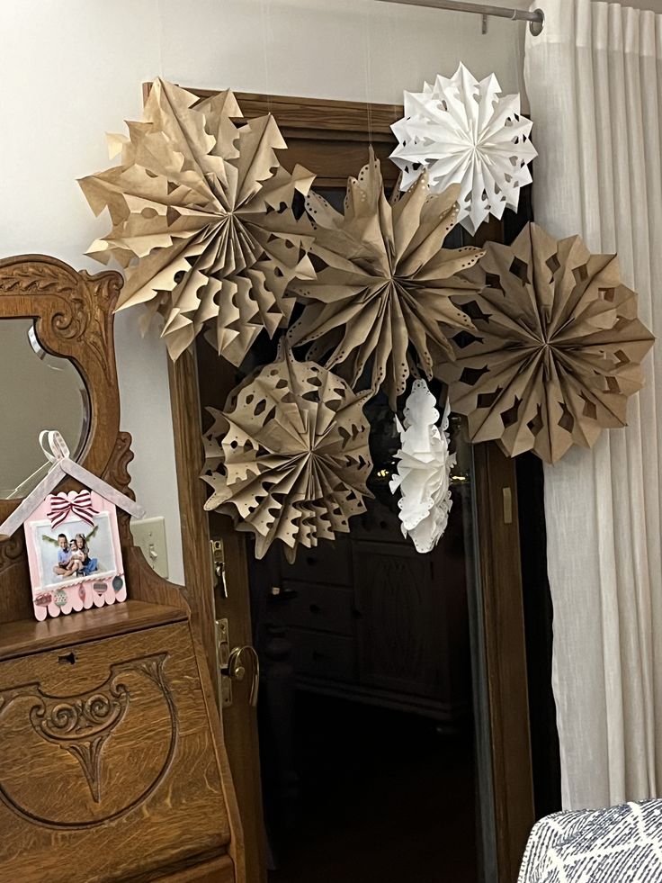 some paper snowflakes hanging from the ceiling in a room with a mirror and dresser