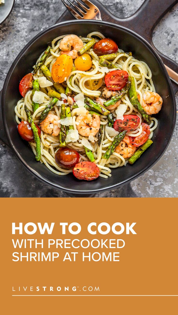 a skillet filled with pasta and shrimp on top of a table next to utensils