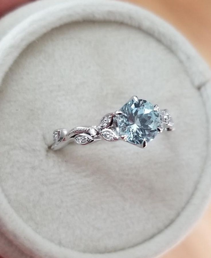 a ring that is sitting on top of a white box with a blue stone in it