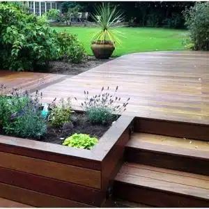 a wooden deck surrounded by plants and flowers