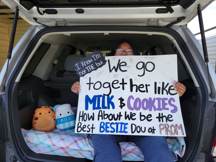 a woman sitting in the back of a car holding a sign that says we go together like milk and cookies