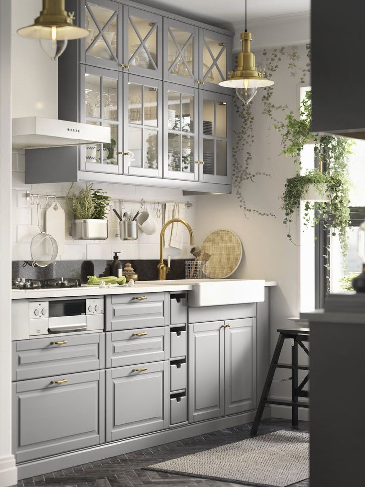 an image of a kitchen setting with grey cabinets and white counter tops, gold accents