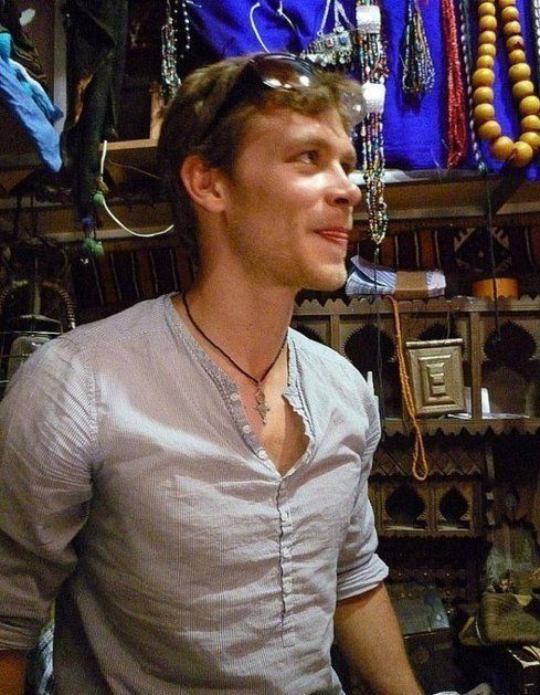 a man standing in front of a display of necklaces and other jewelry hanging from the ceiling